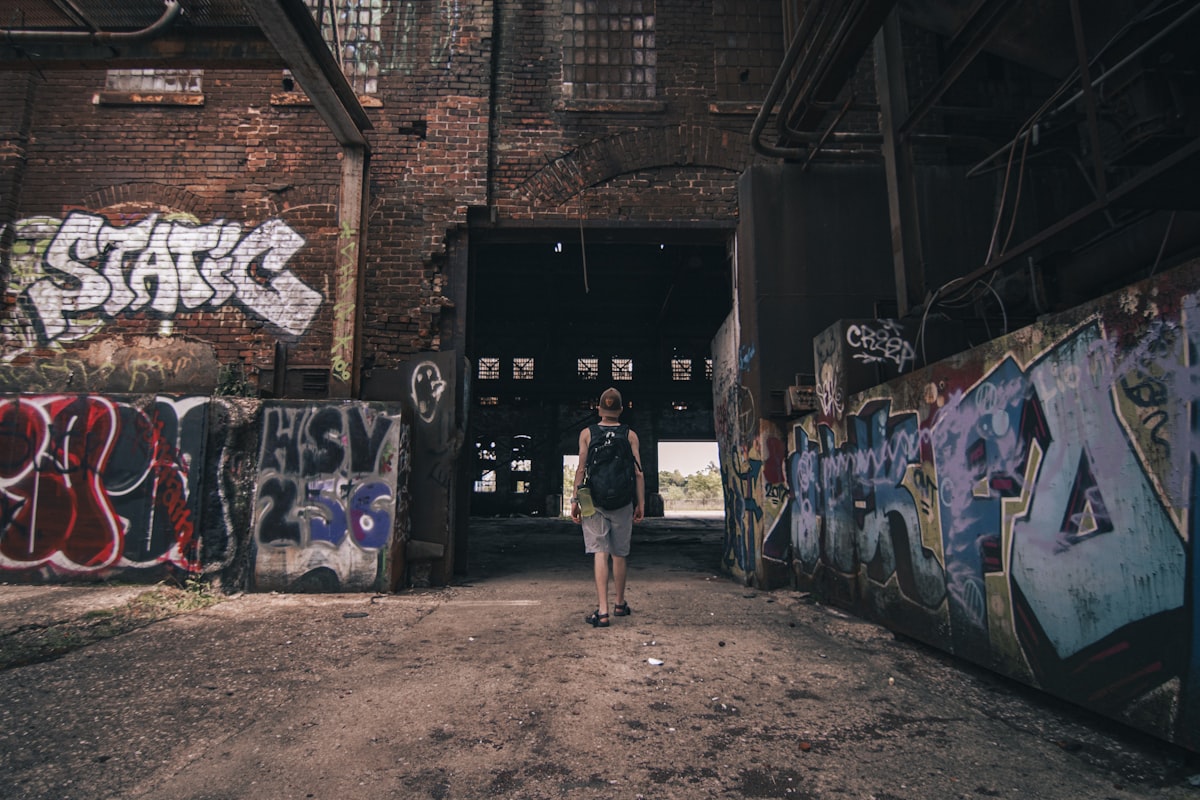 a man standing in a tunnel with graffiti on the walls